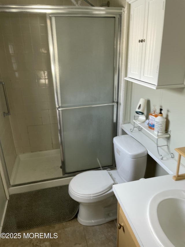 bathroom with a stall shower, vanity, toilet, and tile patterned floors