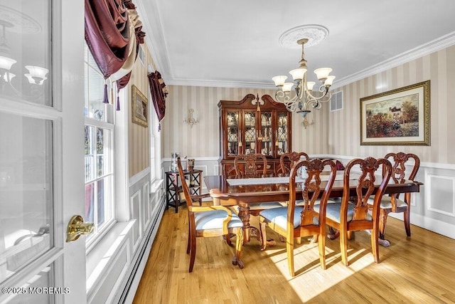 dining space featuring a baseboard heating unit, light hardwood / wood-style flooring, a notable chandelier, and crown molding