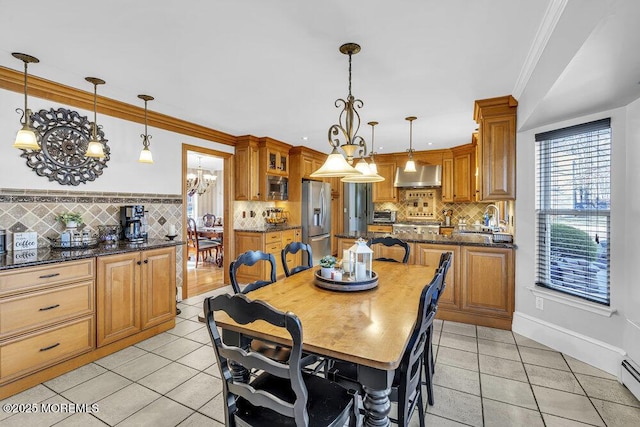 tiled dining area with a baseboard heating unit, a notable chandelier, crown molding, and sink