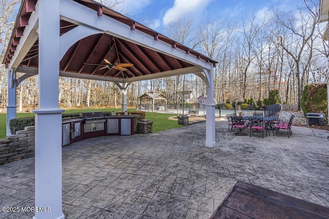 view of patio / terrace featuring a gazebo, ceiling fan, central AC unit, area for grilling, and exterior kitchen