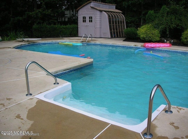 view of swimming pool featuring a diving board and a shed