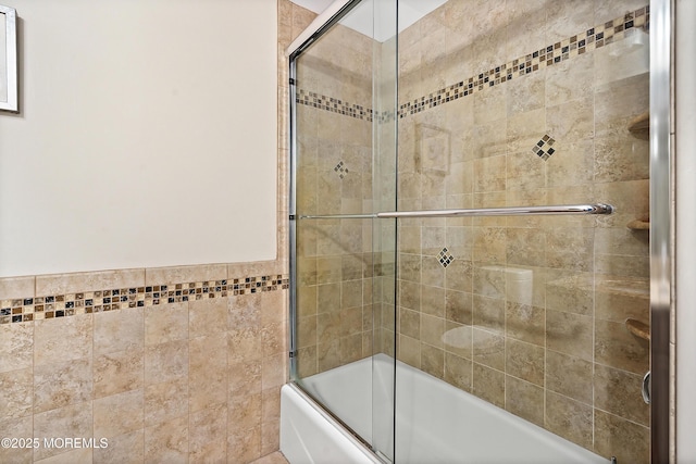 bathroom with shower / bath combination with glass door and tile walls