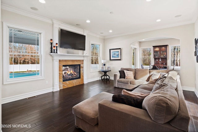 living room featuring dark hardwood / wood-style floors, ornamental molding, and a tiled fireplace