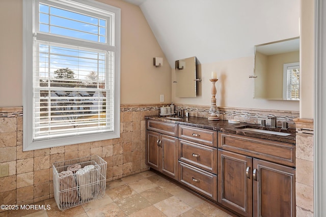 bathroom with tile walls, a wealth of natural light, and lofted ceiling