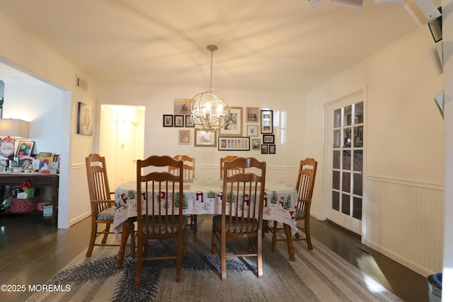 dining space with wood finished floors, visible vents, a wainscoted wall, crown molding, and a chandelier