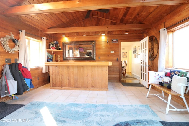 kitchen featuring light tile patterned floors, lofted ceiling with beams, wood walls, and wooden ceiling