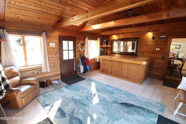 living room with beam ceiling, wooden walls, light tile patterned floors, and wood ceiling