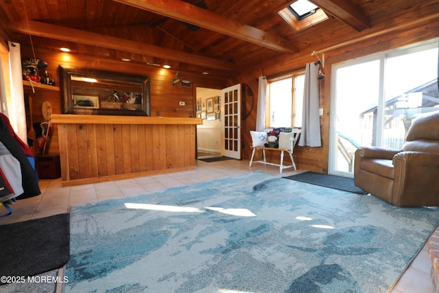 living area with wooden walls, bar area, wood ceiling, vaulted ceiling with skylight, and tile patterned floors