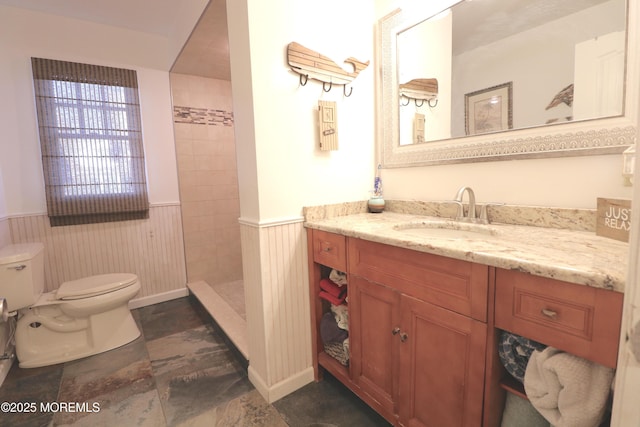 full bathroom with wainscoting, a walk in shower, toilet, and vanity