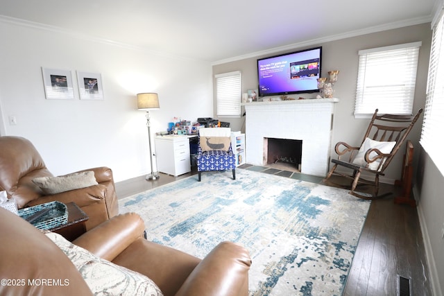 living area with crown molding, hardwood / wood-style flooring, a brick fireplace, and visible vents