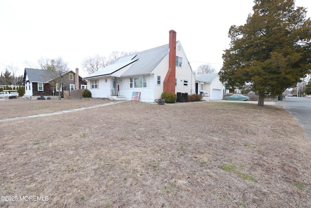 view of front of home with solar panels, a chimney, and a garage