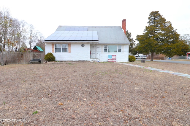 view of front of house with solar panels, fence, and a chimney