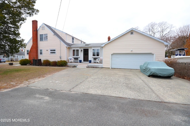 view of front facade with a garage, driveway, and a chimney