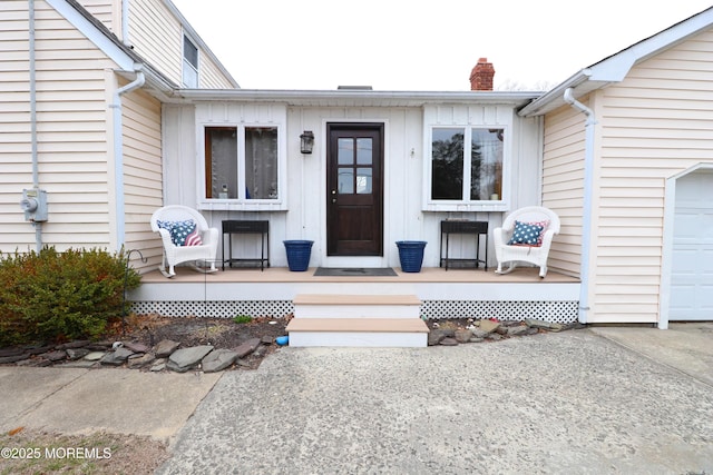 entrance to property with a garage, a porch, and a chimney