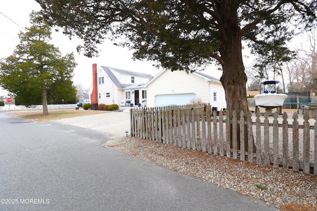 view of front of house with driveway, a trampoline, an attached garage, and fence