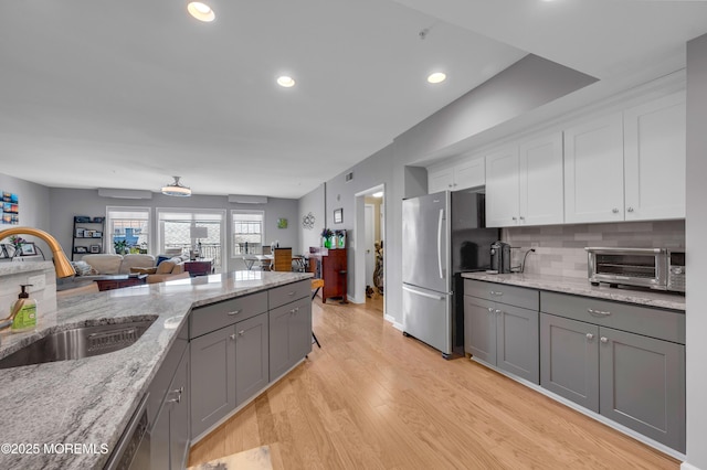 kitchen featuring decorative backsplash, appliances with stainless steel finishes, light stone counters, sink, and white cabinets