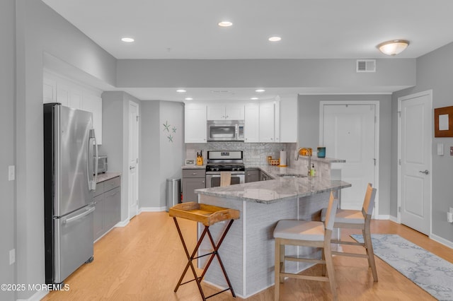 kitchen featuring sink, stainless steel appliances, kitchen peninsula, a breakfast bar area, and white cabinets