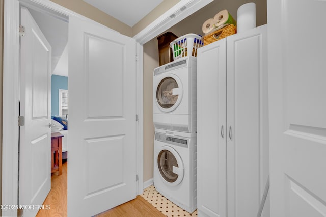 clothes washing area featuring light hardwood / wood-style floors and stacked washer / drying machine