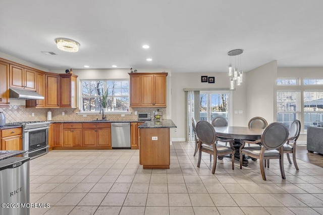 kitchen featuring pendant lighting, sink, dark stone countertops, stainless steel appliances, and light tile patterned flooring