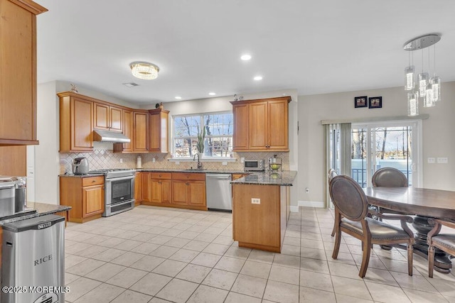 kitchen with sink, stainless steel appliances, light tile patterned flooring, decorative light fixtures, and dark stone counters