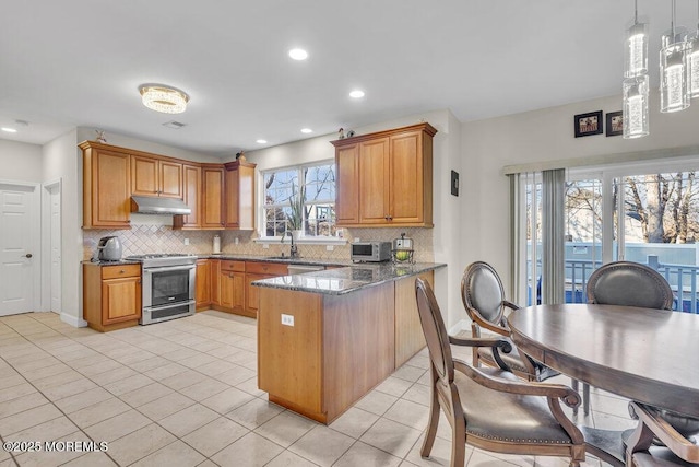 kitchen with pendant lighting, dark stone countertops, light tile patterned floors, kitchen peninsula, and gas range