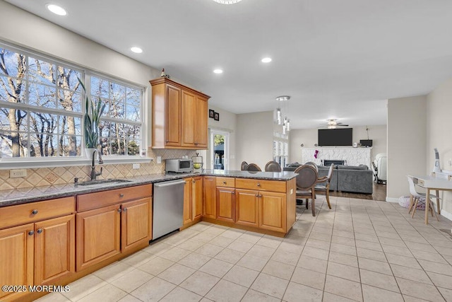 kitchen with sink, light tile patterned floors, tasteful backsplash, stainless steel dishwasher, and kitchen peninsula