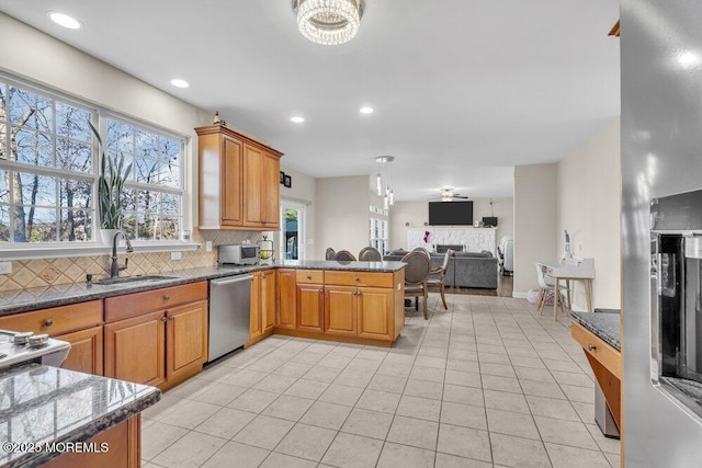 kitchen featuring tasteful backsplash, dishwasher, sink, dark stone countertops, and light tile patterned floors