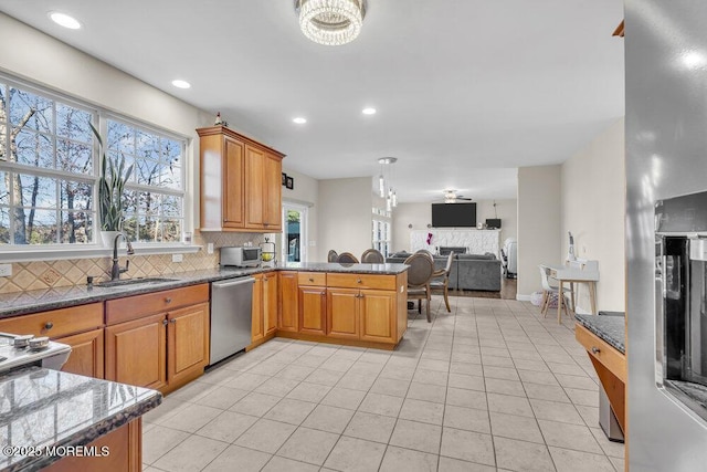 kitchen with appliances with stainless steel finishes, sink, dark stone countertops, and light tile patterned floors