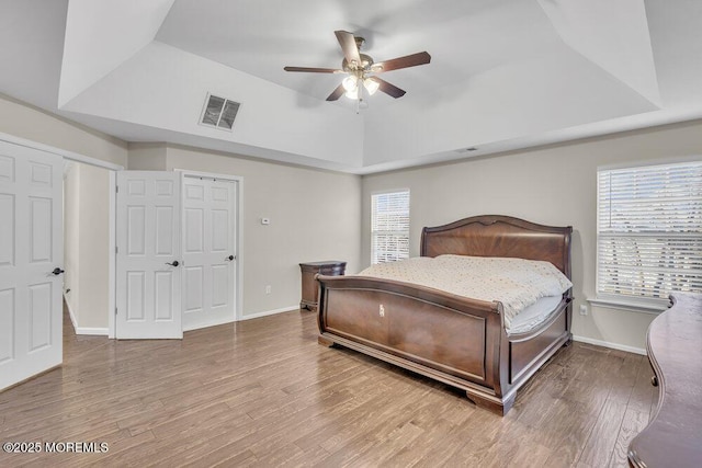 bedroom with a raised ceiling, hardwood / wood-style floors, and ceiling fan