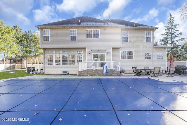 back of property with a covered pool and a patio area