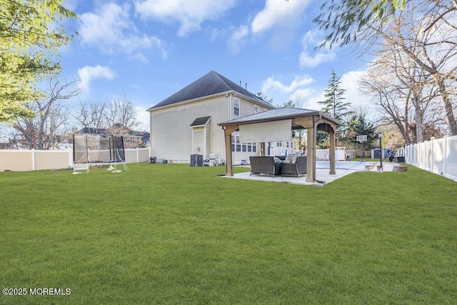 rear view of property with cooling unit, a patio area, a trampoline, and a lawn