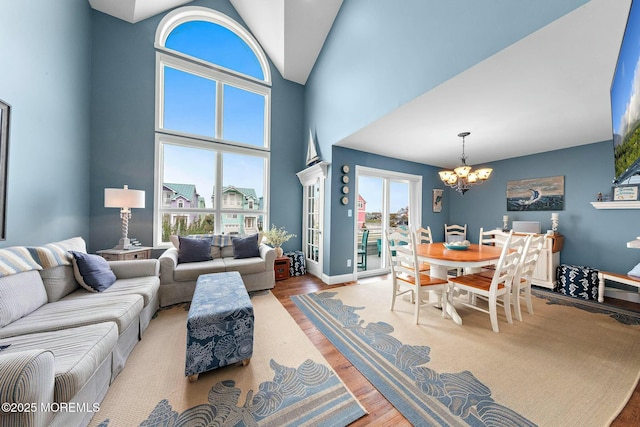 living room with high vaulted ceiling, light wood-type flooring, and an inviting chandelier