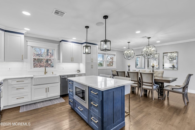 kitchen with visible vents, blue cabinetry, wood finished floors, stainless steel appliances, and a sink