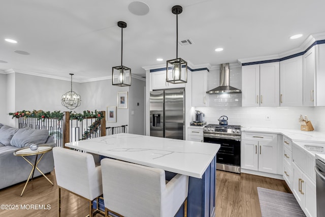 kitchen with visible vents, tasteful backsplash, wood finished floors, stainless steel appliances, and wall chimney exhaust hood