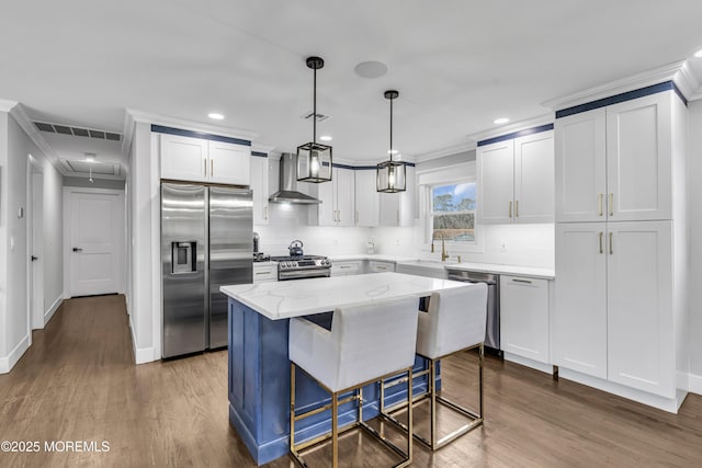 kitchen with visible vents, crown molding, appliances with stainless steel finishes, wall chimney exhaust hood, and a sink