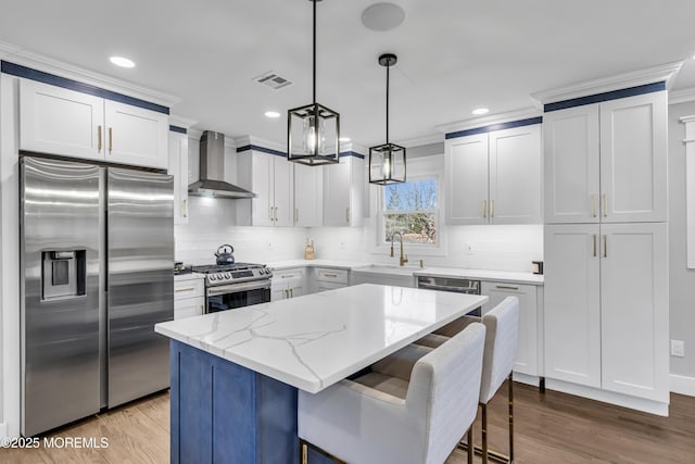 kitchen with visible vents, light stone countertops, stainless steel appliances, wall chimney exhaust hood, and a sink