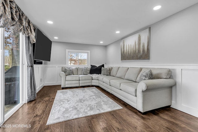 living room featuring dark wood-type flooring, a decorative wall, and recessed lighting