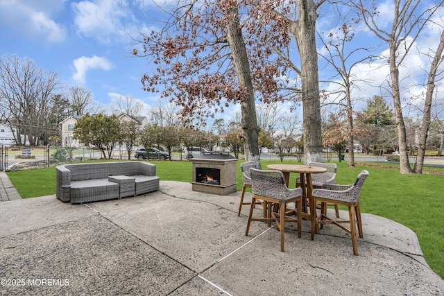 view of patio featuring a warm lit fireplace and fence