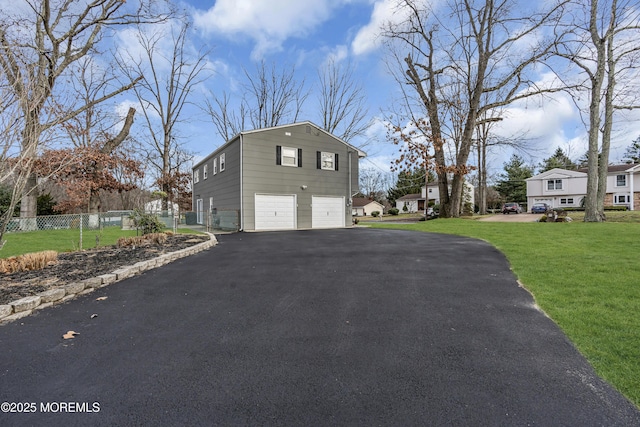 view of property exterior with aphalt driveway, a lawn, a garage, and fence