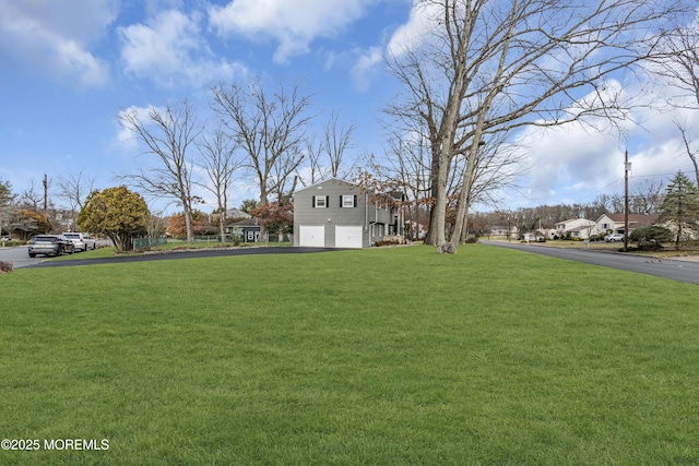 view of yard with aphalt driveway and an attached garage