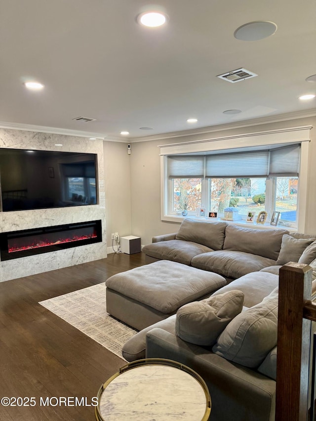 living room featuring wood finished floors, visible vents, a high end fireplace, ornamental molding, and a wealth of natural light