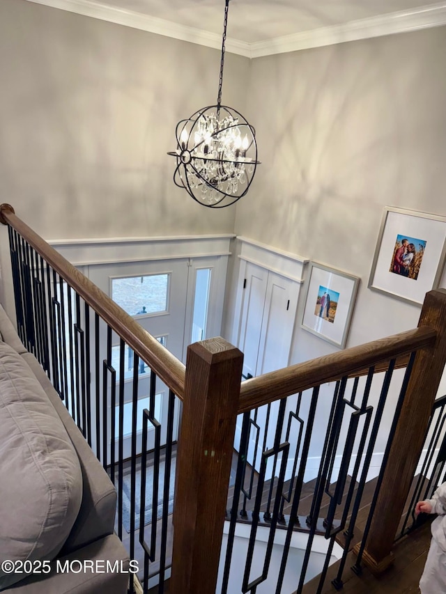 stairs featuring crown molding, wainscoting, and a chandelier