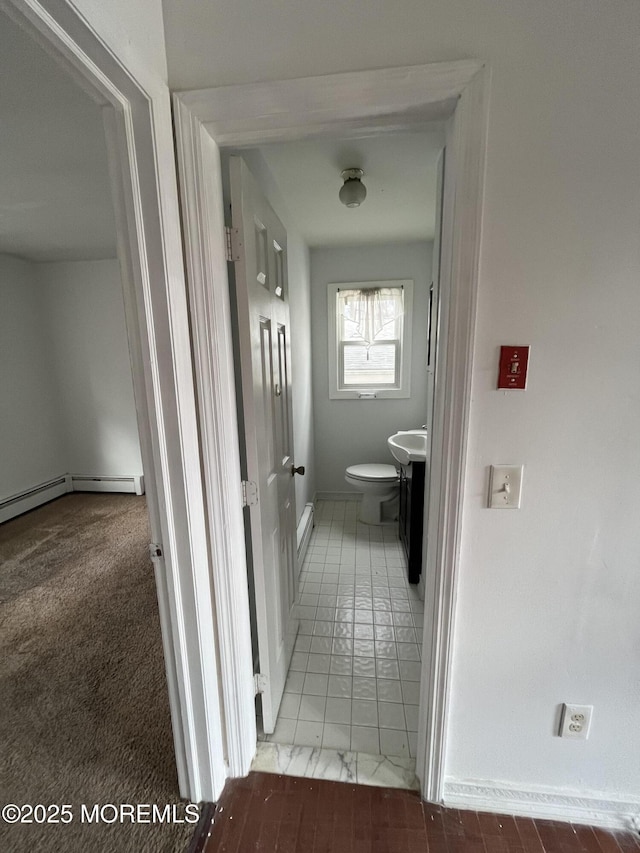 hallway with a baseboard radiator, a sink, and baseboards