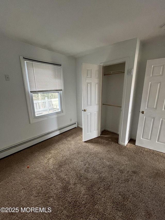 unfurnished bedroom with carpet, a closet, and baseboard heating