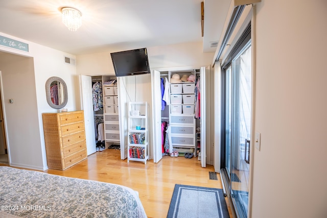 bedroom with wood-type flooring, an inviting chandelier, and a closet