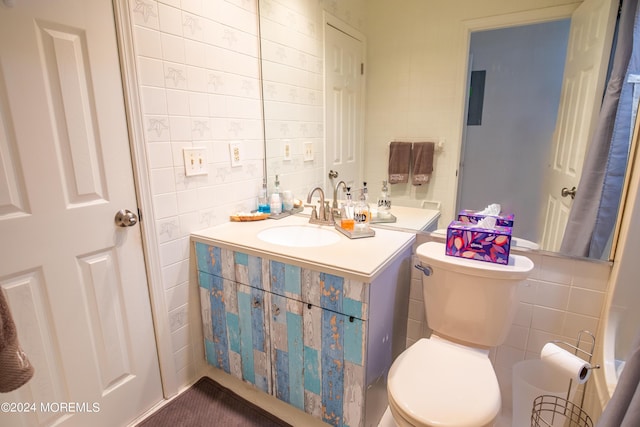 bathroom featuring vanity, toilet, and tile walls