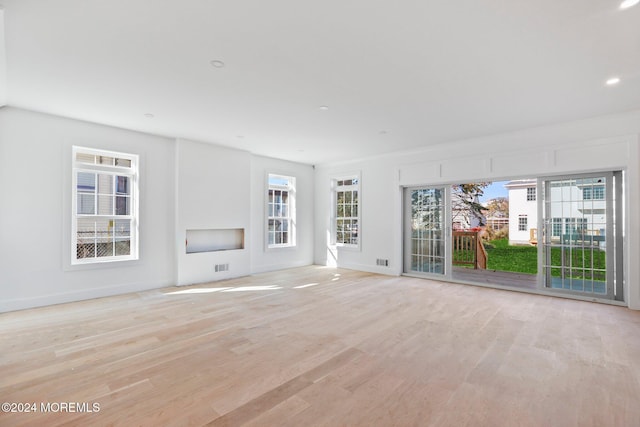 unfurnished living room featuring plenty of natural light and light hardwood / wood-style flooring