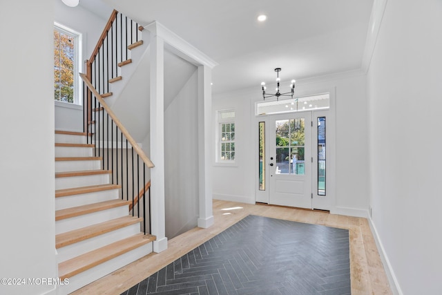 foyer featuring crown molding, light wood-type flooring, and a notable chandelier
