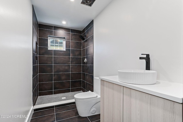 bathroom featuring tile patterned flooring, vanity, toilet, and a tile shower