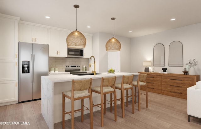 kitchen with a center island with sink, sink, decorative backsplash, decorative light fixtures, and stainless steel appliances